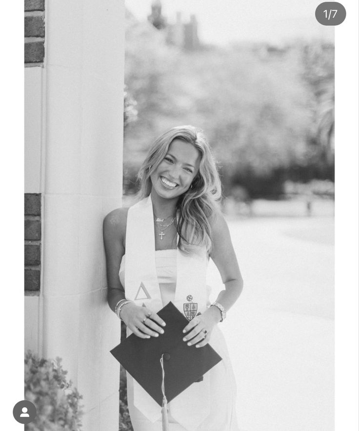 black and white photograph of a smiling woman leaning against a column with her hands in her pockets