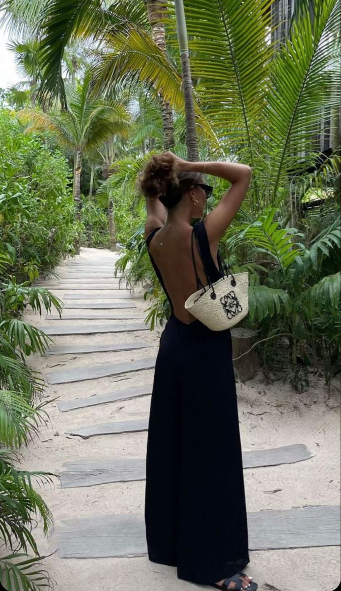 a woman in a black dress is standing on the path with her back to the camera