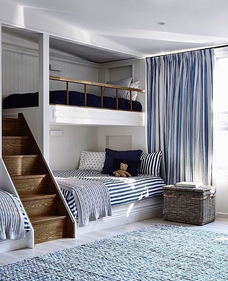 bunk beds with blue and white striped sheets in a child's bedroom, next to a stair case