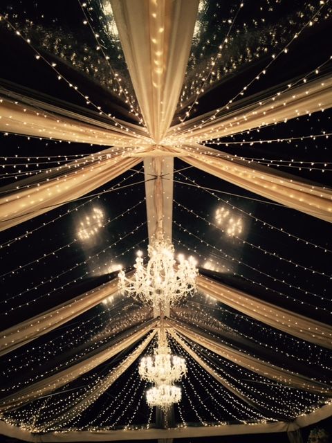 the inside of a tent with chandeliers and lights