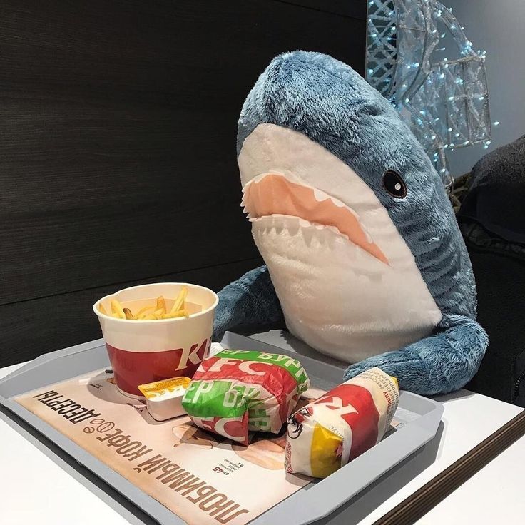 a stuffed shark sitting on top of a table next to chips and ketchup