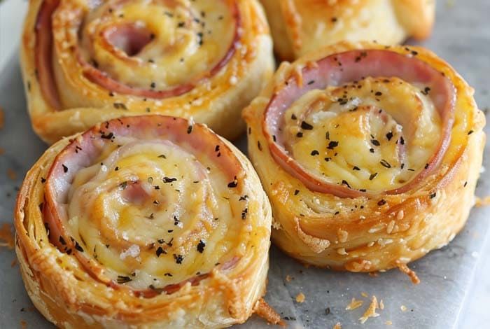 ham and cheese pinwheels are shown on a baking sheet, ready to be eaten