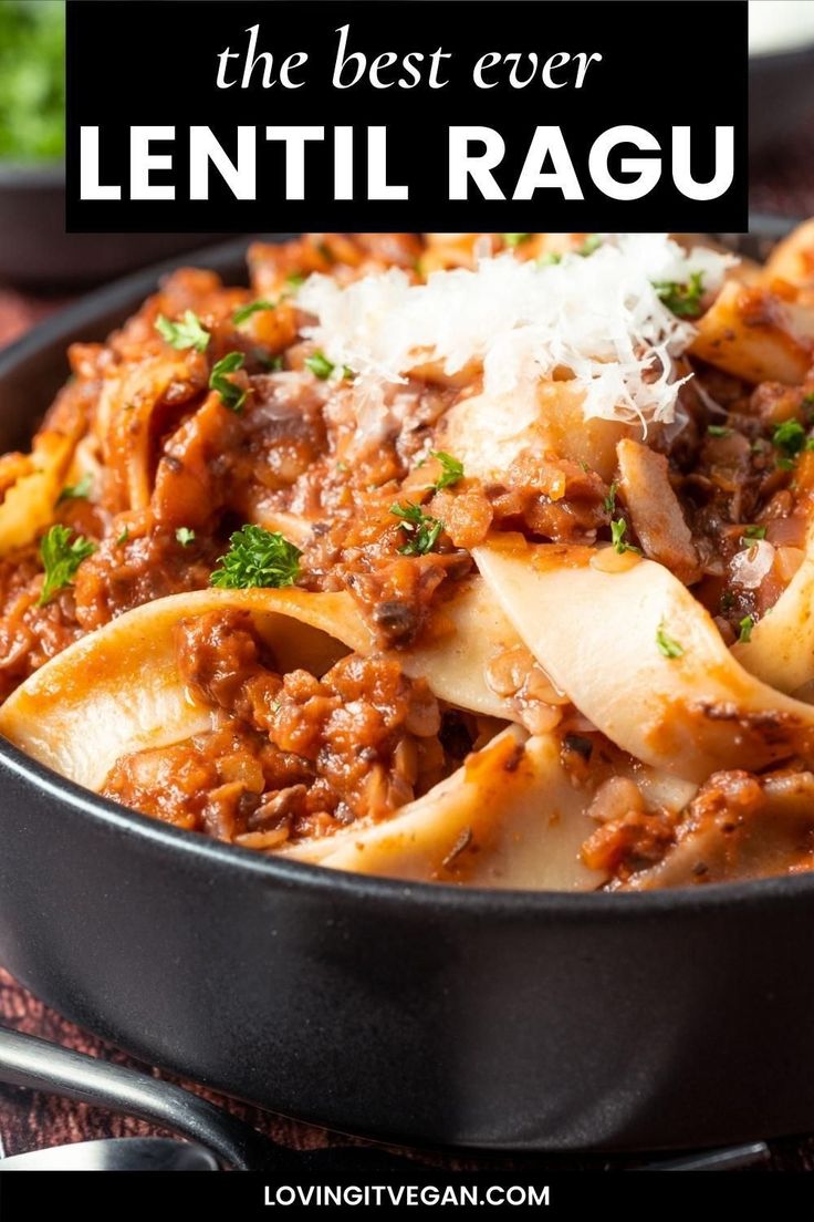 a skillet filled with pasta and sauce on top of a red table cloth next to silverware