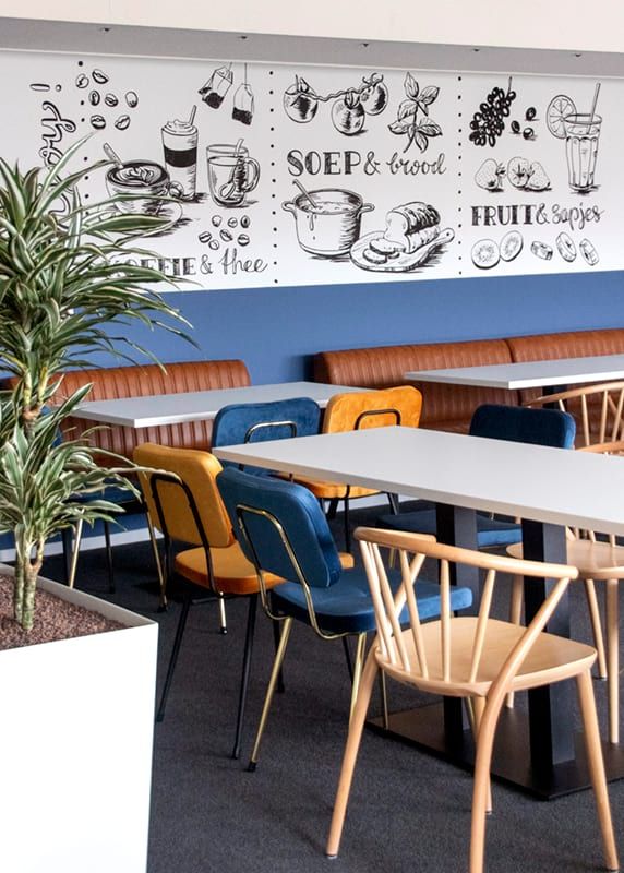 an empty restaurant with blue walls and wooden chairs