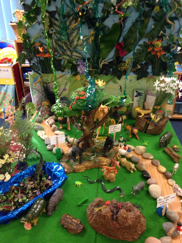 an assortment of plants and rocks on a green carpeted floor in front of a tree