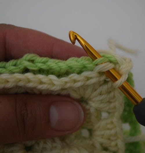 the crochet stitch is being worked on by a person holding a knitting needle