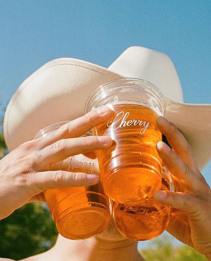 a woman wearing a cowboy hat drinking from a mason jar with the word henry written on it