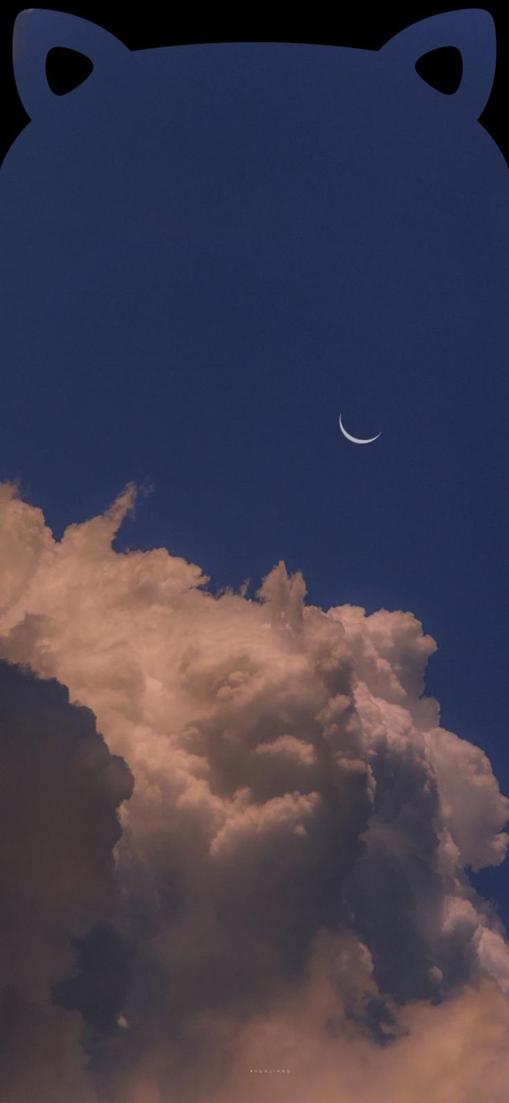 the moon is seen in the sky above clouds and a bear head silhouetted against a dark blue sky