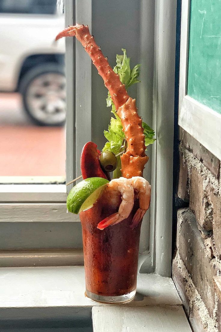 a tall glass filled with different types of food on top of a window sill