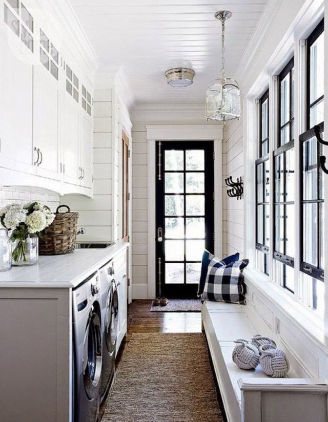 a long hallway with white cabinets and black door, window sill, washer and dryer