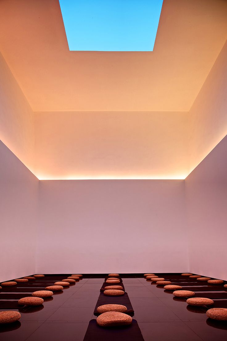 an empty room with benches and skylight in the ceiling is lit by lights from above