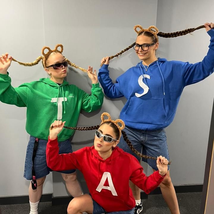 three people in costumes are posing for the camera with their hands up and one person is holding on to ropes