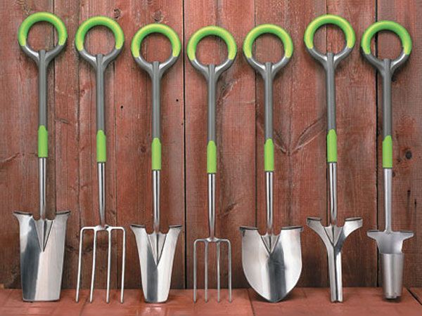 several different types of garden tools lined up against a wooden wall with green handles and tips