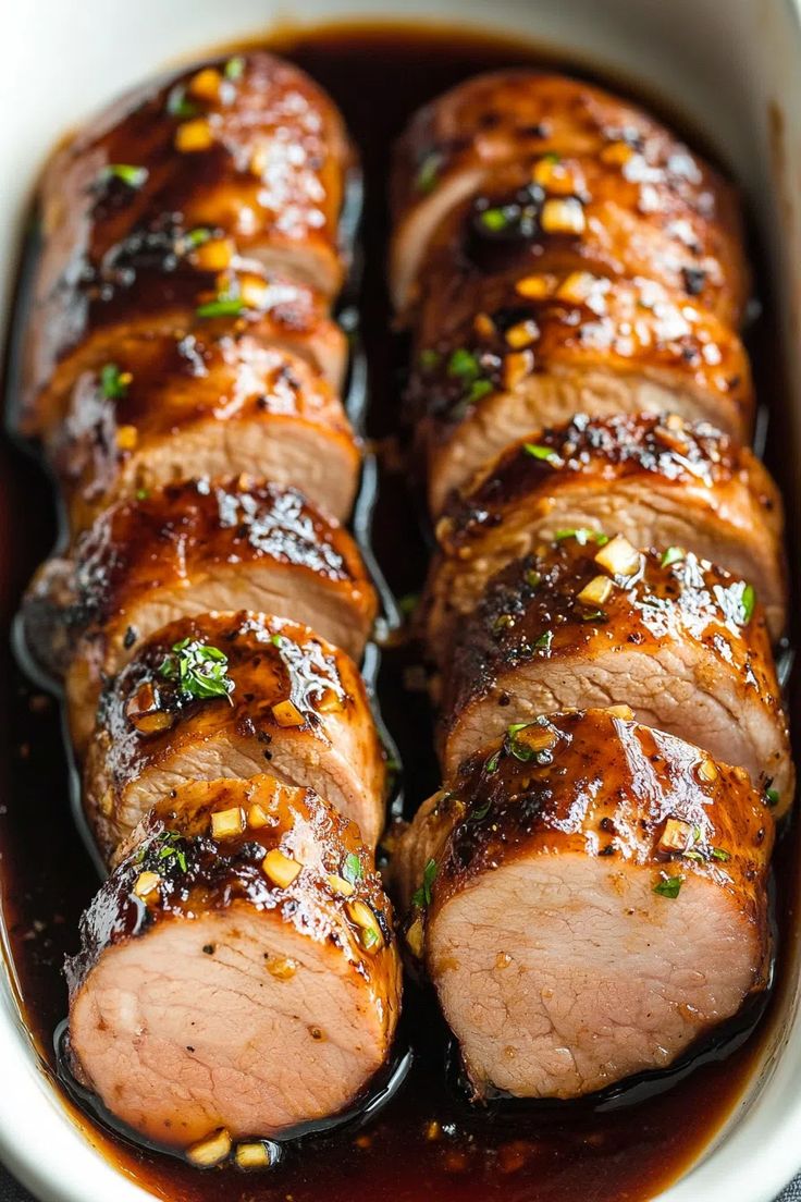 sliced pork with sauce and garnish in a white dish