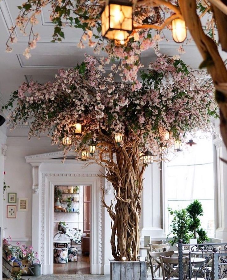 a large tree in the middle of a room with lots of flowers growing on it