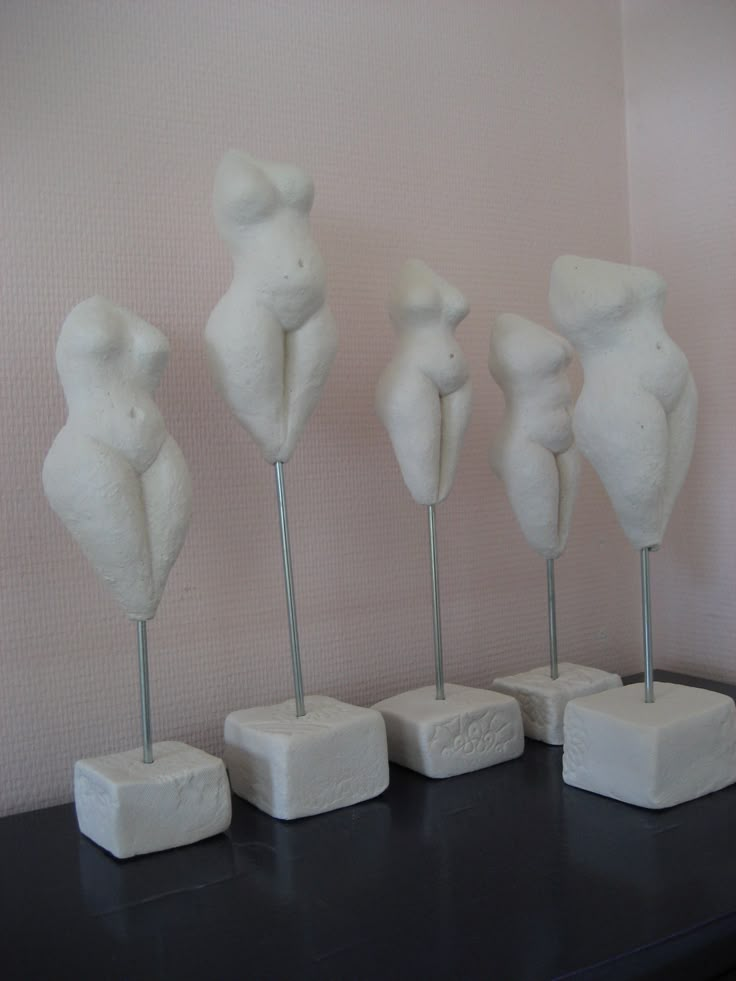 five white sculptures are lined up on a black table