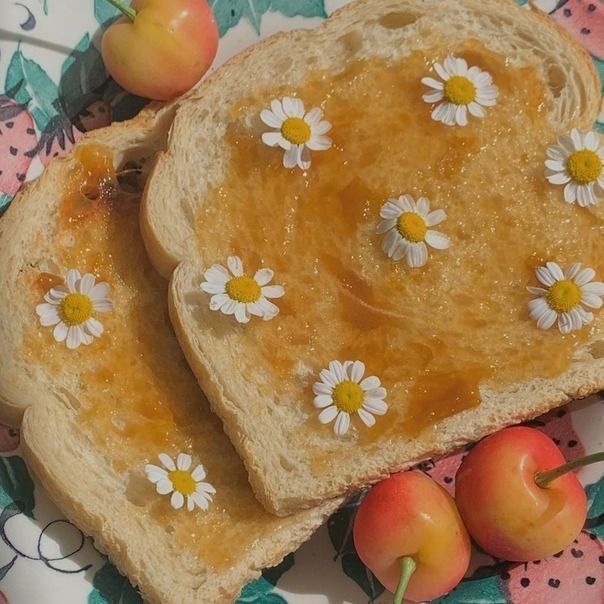 two pieces of bread with white flowers on them and some apples in the foreground