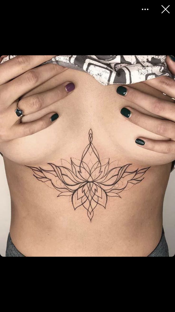 a woman's stomach with a lotus tattoo on the side and her hands behind her head