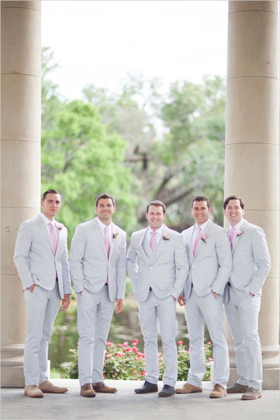 a group of men standing next to each other in front of some tall pillars and trees