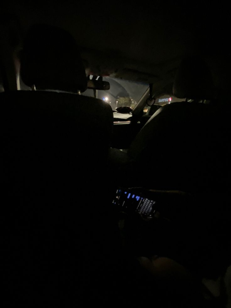 the interior of a car at night with headlights on and people sitting in the passenger seat