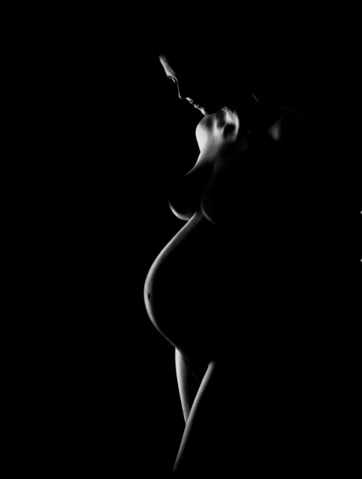 black and white photograph of a woman's breast in the dark with her eyes closed