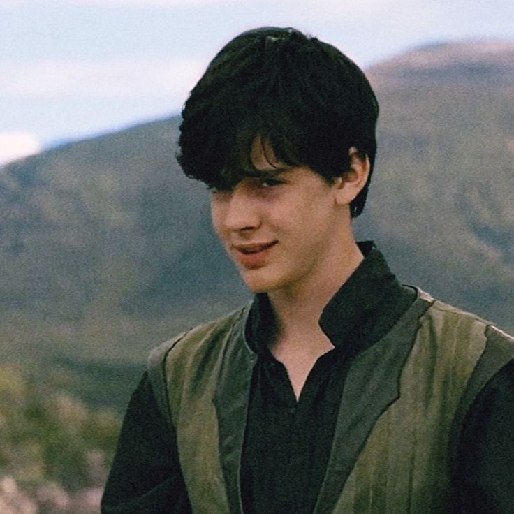 a young man standing in front of a mountain