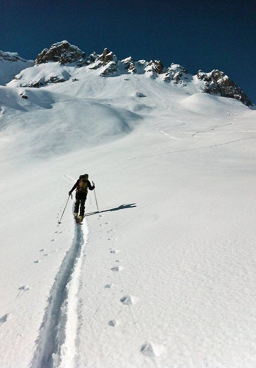 a man riding skis down the side of a snow covered slope next to a mountain