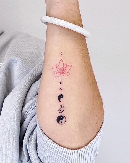 a woman's arm with a tattoo on it that has three black circles and a pink flower