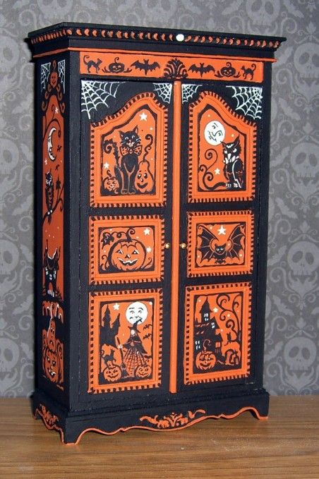 an orange and black cabinet with halloween decorations on the front, sitting on a wooden table