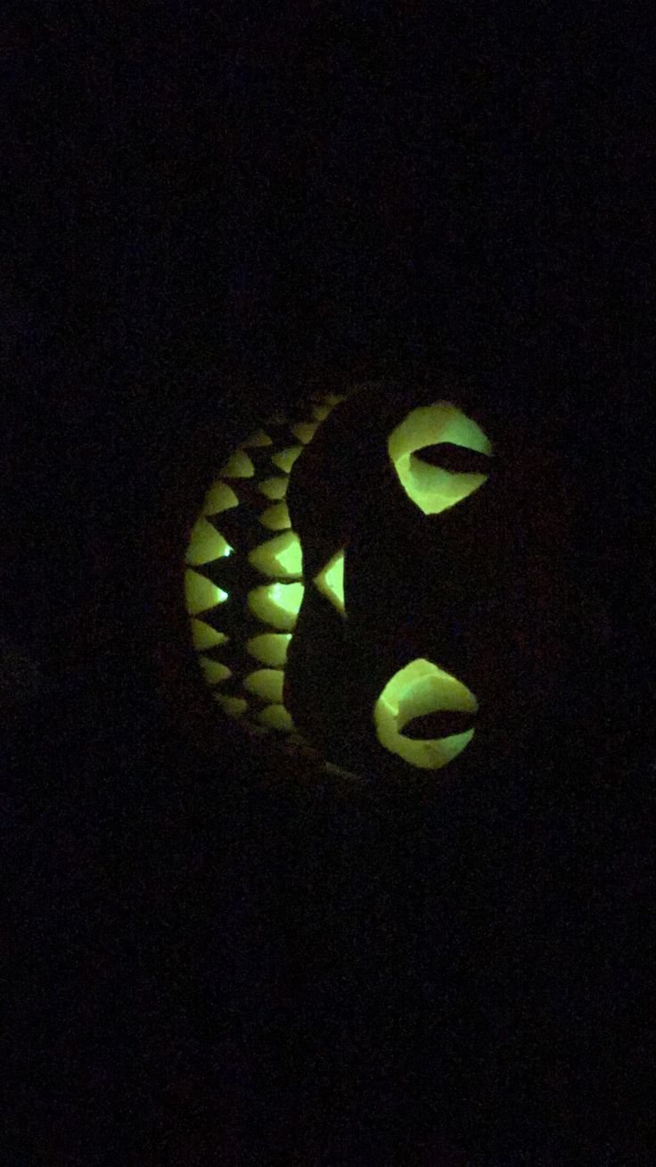 a carved pumpkin in the dark with green lights