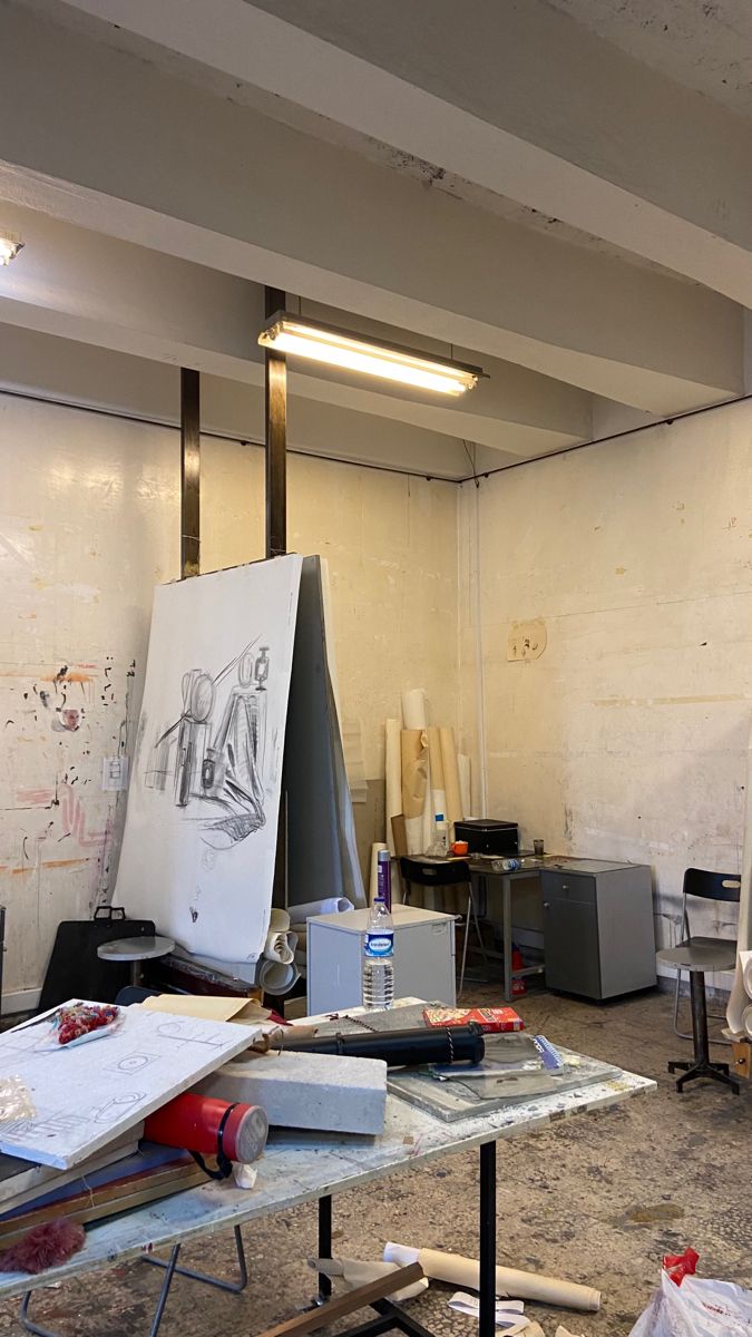 an art studio with various items on the table and in front of it is a drawing easel