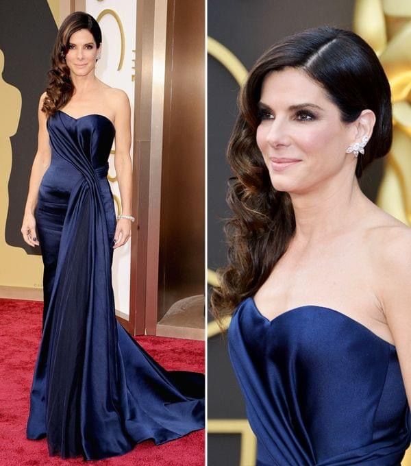 a woman in a blue dress on the red carpet at an oscars event with her hair pulled back