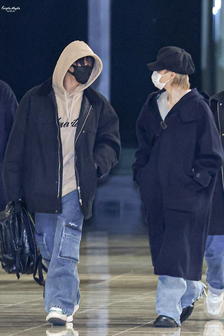 two people wearing face masks walk through an airport