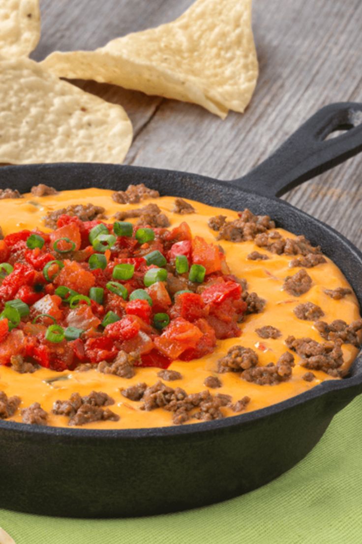 a skillet filled with chili cheese and tortilla chips on a wooden table