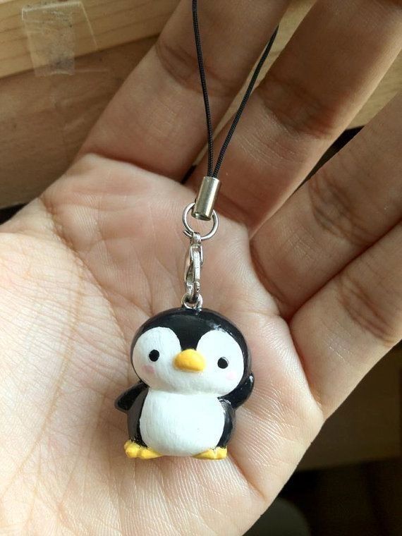 a small penguin keychain hanging from a person's hand