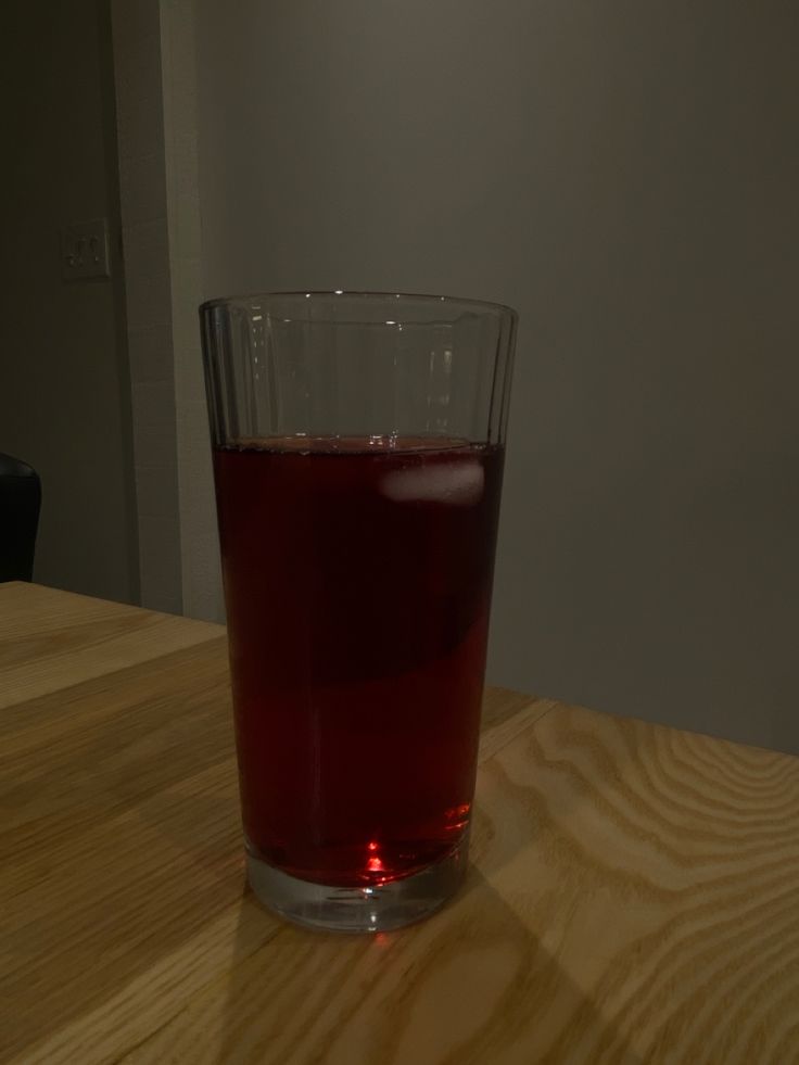 a glass filled with liquid sitting on top of a wooden table