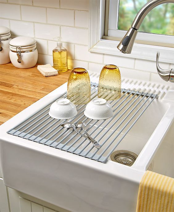 a kitchen sink with two glasses on the bottom and a towel hanging from the faucet