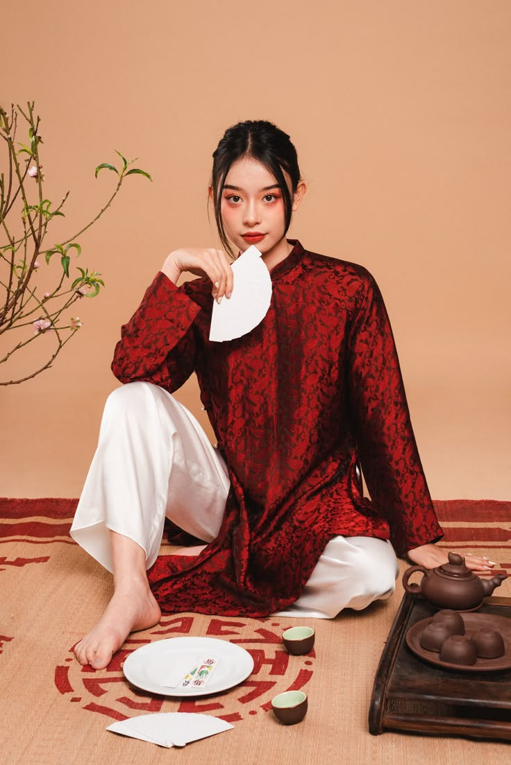 a woman is sitting on the floor next to some plates and teapots, holding a paper towel