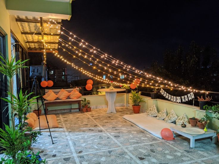 an outdoor seating area with lights strung over it