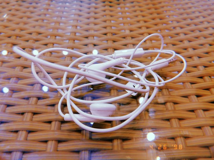 an apple earbuds laying on a wicker table with light reflecting off the surface