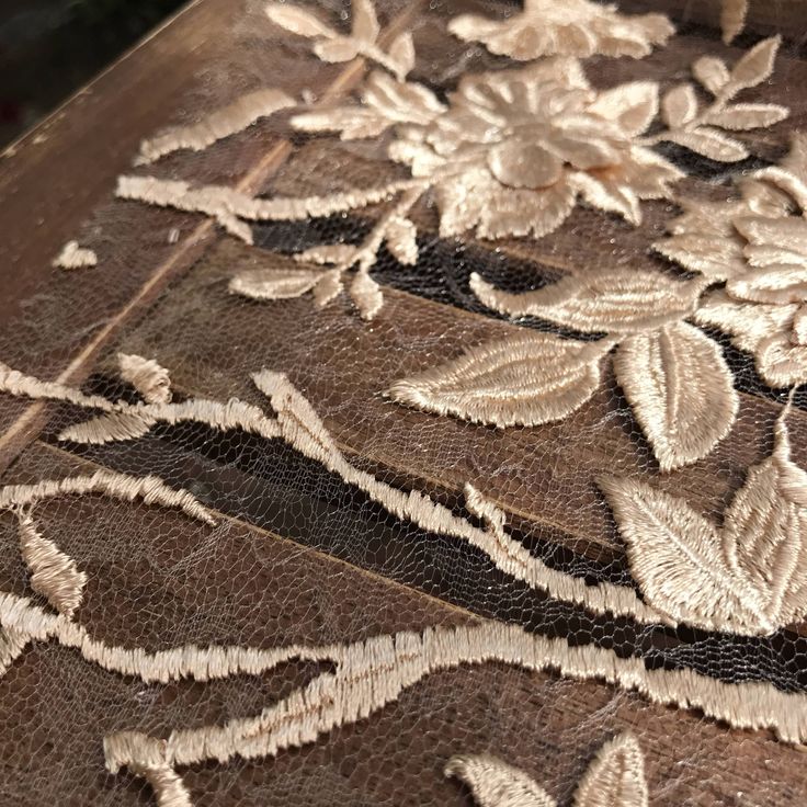 an intricately designed piece of cloth with leaves and flowers on the fabric is being stitched together