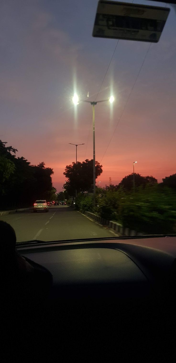 the sun is setting behind some street lights