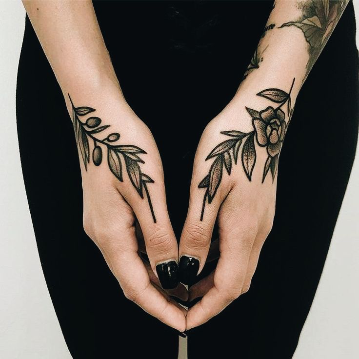 two hands with tattoos on them holding a knife in the shape of a flower and leaves