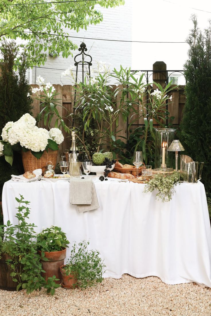 a table covered with white flowers and potted plants