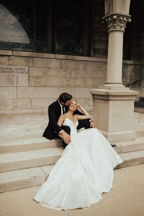 a bride and groom are sitting on the steps in front of a building with columns