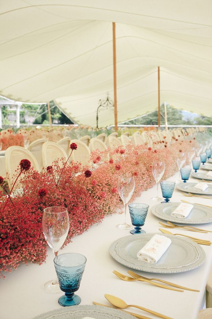 the tables are set with blue and white plates, silverware, and flowers in vases