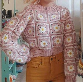 a woman standing in front of a mirror wearing a pink sweater with flowers on it