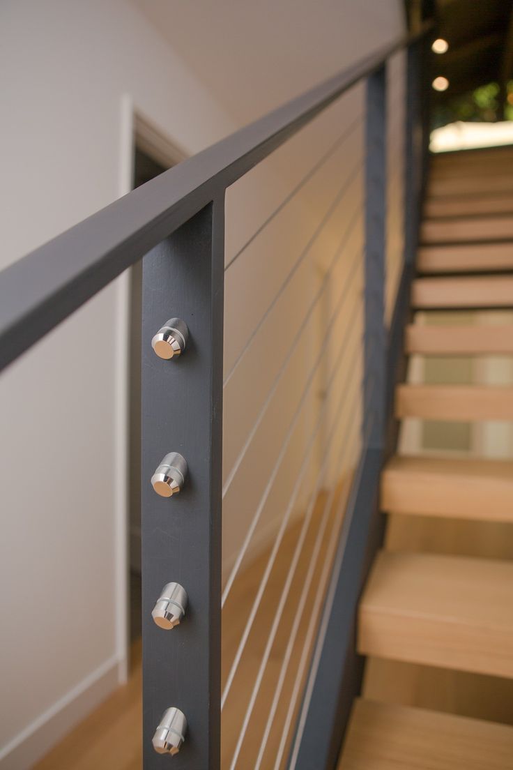 there are three knobs on the railing of this stair case that is made of metal