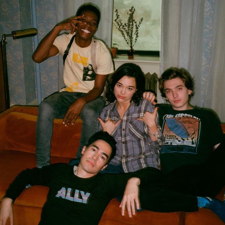 three people sitting on a couch posing for the camera with their fingers in the air