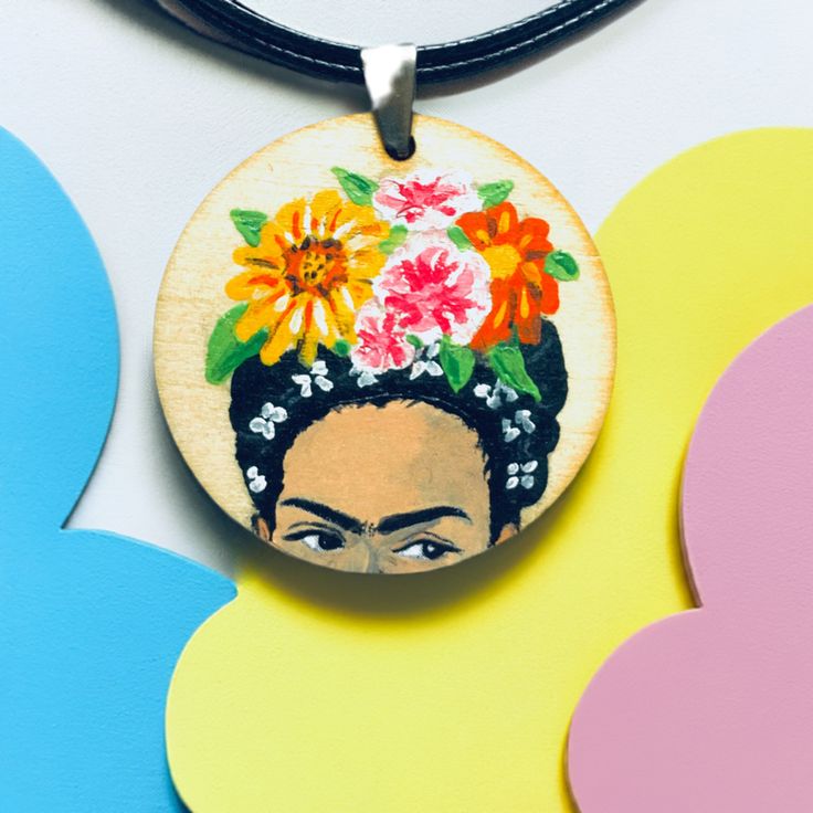 Experience the vibrant spirit of Frida Kahlo with this gorgeous hand-painted floral pendant-necklace. Frida-inspired jewelry that captures her iconic spirit and style. Each piece is adorned with intricate details and vibrant hues created with premium acrylic paints. This lightweight round wooden pendant features a beautifully painted portrait, making it the perfect gift for any Frida fan. Celebrate Mexico's iconic artist and add a touch of color to your wardrobe. Are you a Fridamaniac? This one-of-a-kind chic necklace is for you! This pendant is sure to make a statement and make a fantastic gift for that special someone in your life. DETAILS/MEASURES: Size: It is about 1.5 inches diameter and the waxed cotton cord is approximately 24 inch long.Material: Wood and acrylic paint._____________ Hand Painted Pendants Necklaces, Luxury Hand Painted Pendant Necklaces, Nature-inspired Hand Painted Pendant Necklace, Frida Kahlo Earrings, Vintage Hand-painted Pendant Necklace, Bohemian Embroidered Pendant Necklace, Mexican Earrings, Floral Pendant Necklace, Handpainted Bags